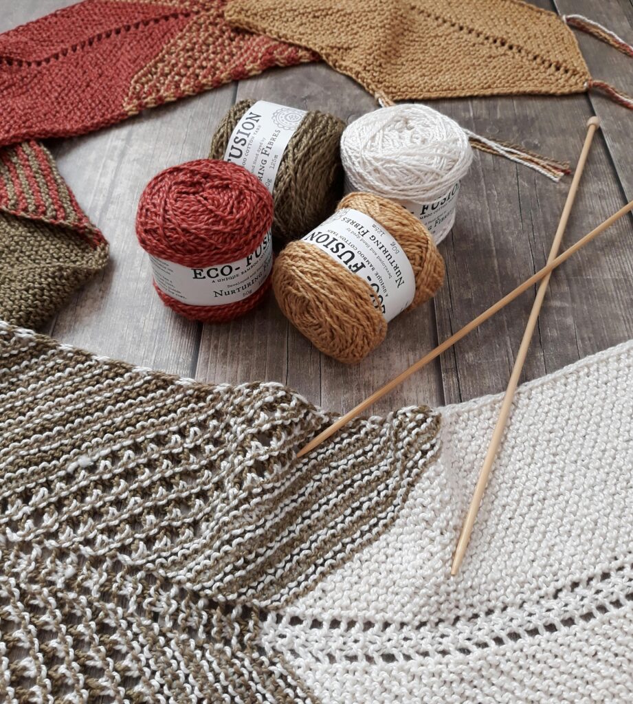 Colorful yarns and knitting needles for creating handmade crafts on a wooden surface.