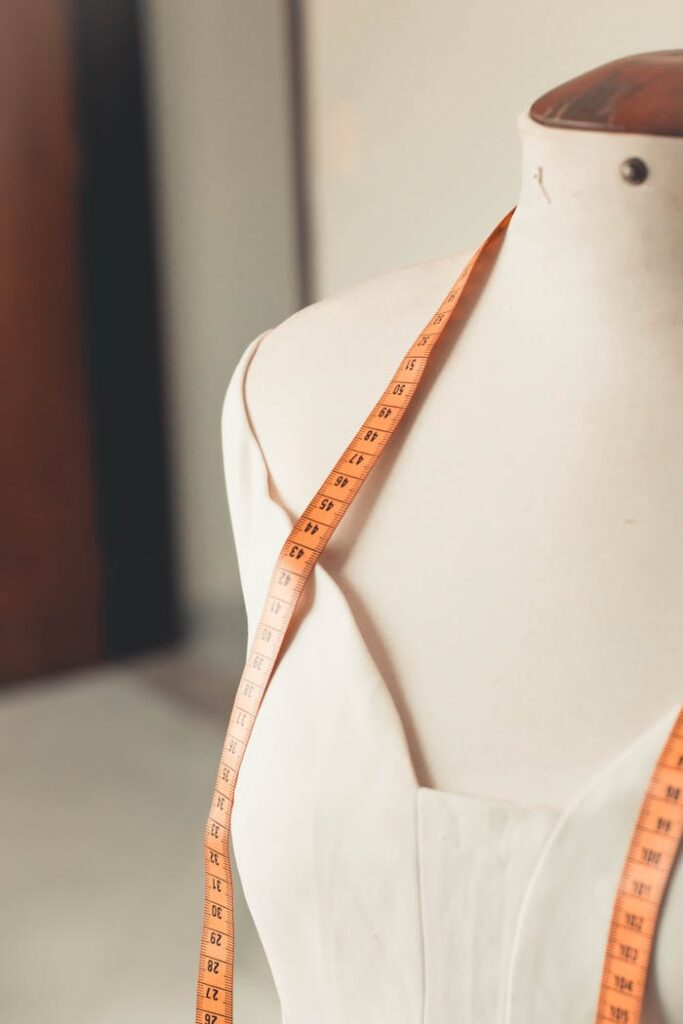 A close-up of a mannequin with a measuring tape draped over, depicting fashion design and tailoring.