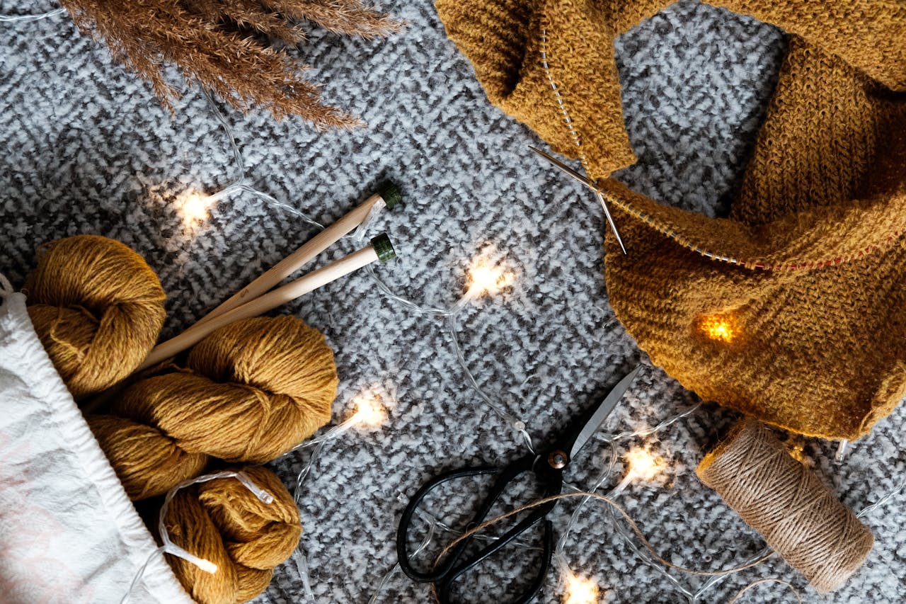 Close-up of cozy knitting setup with yarn, needles, and lights, perfect for creative winter crafts.