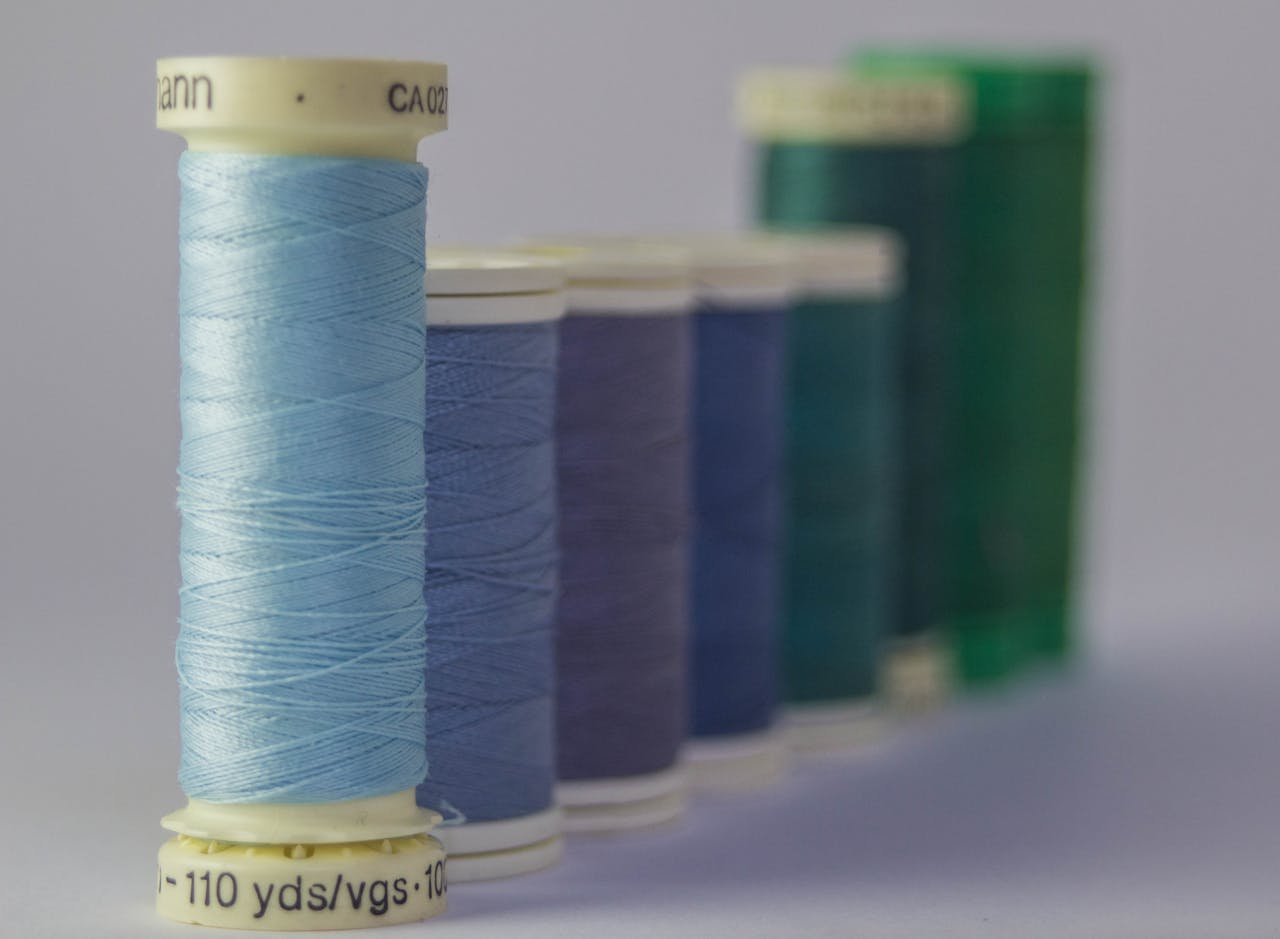 Close-up of colorful sewing thread spools aligned indoors, showcasing vivid hues and textures.